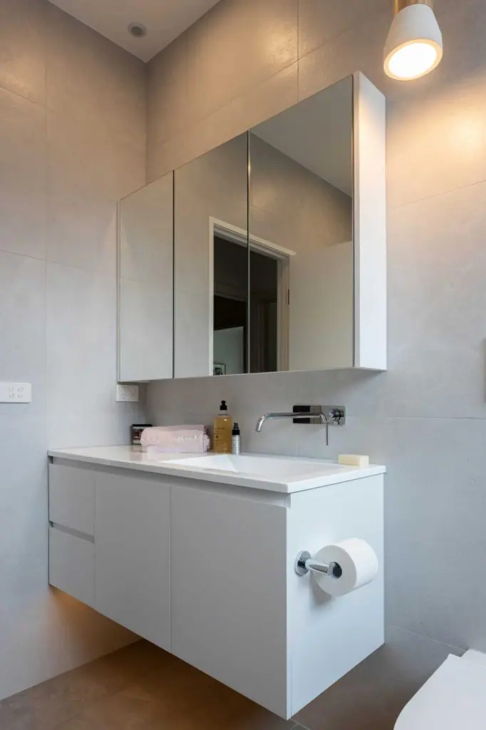 white vanity with mirror storage cabinet and chrome wall tap